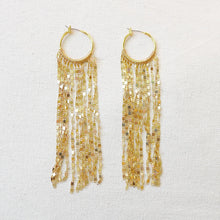 Load image into Gallery viewer, Pair of IP gold-plated hoop earrings with long cascading faceted gold chain strands, displayed on a soft white textured background.