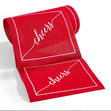 Load image into Gallery viewer, Roll of red cotton cocktail napkins with a white border and "cheers" in white script, displayed on a white surface. 
