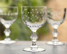 Load image into Gallery viewer, Stemmed goblet with small etched stars. Two more goblets are blurred in the background. All sitting on a wooden platform. Blurred nature background. 