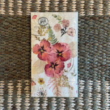 Load image into Gallery viewer, Michel Design Works Pressed Flowers hostess napkins in packaging featuring red and pink floral design on a light background, displayed on a woven surface. 