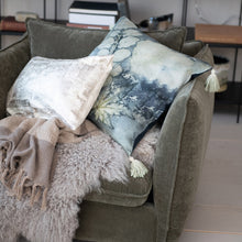Load image into Gallery viewer, Blue Velvet Pillow, styled on beige upholstered chair with abstract blue-toned design and faded white botanical pattern, with white tassels at each corner alongside neutral accent pillow and throws in a living space. 