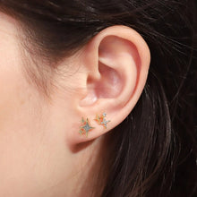 Load image into Gallery viewer, Close-up of model wearing gold-plated starburst stud earrings with small clear crystal details worn on the ear.