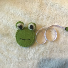 Load image into Gallery viewer, Green frog felt measuring tape on a beige carpet. 