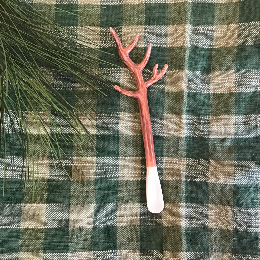 Small matcha spoon with the handle in a shape of an antler. Background is a green checked cloth. 