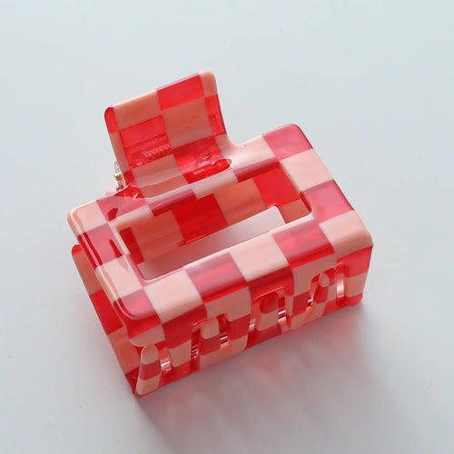 A pink and red checkered claw clip for hair, on a white surface.