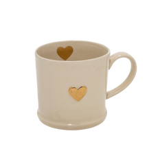 Load image into Gallery viewer, White stoneware mug with a gold heart design on the front and inside rim area. 