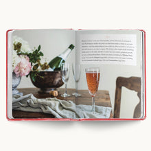 Load image into Gallery viewer, Open "Romantic Cocktails" recipe book with photo of a pink sparkling drink in a champagne flute on a wooden table.