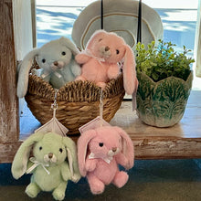 Load image into Gallery viewer, Assorted plush bunny bag charms with floppy ears, ribbon bows, and silver lobster clasps clips in lime green, pink, light blue, and peach, displayed in and hanging from a woven basket. 