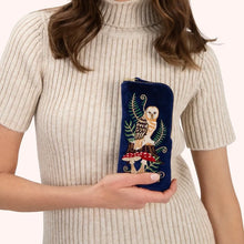 Load image into Gallery viewer, Person wearing a cream ribbed turtleneck sweater holding a navy blue velvet zippered sunglass pouch with embroidered tan and brown owl, red mushrooms, and green ferns, against a white background. 