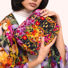 Load image into Gallery viewer, Botanical Kaleidoscope Quilted Velvet Washbag, model wearing a matching kimono holding rectangular zippered bag featuring a quilted finish and vibrant multicolored floral rainforest pattern against a white background. 