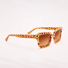 Load image into Gallery viewer, Demi Toasted Moxie Checkered Sunglasses, angled view of square textured acetate sunglasses with brown, cream, amber, and mustard yellow checkered frames and arms and brown gradient lenses, displayed against a white background. 
