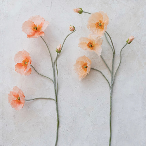Two pink faux poppy flower stem picks on a light gray background.