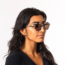 Load image into Gallery viewer, Georgie Cosmic Cowboy Sunglasses, model wearing round sunglasses with black, cream, and brown marbled frames and dark brown tinted lenses against white background.