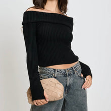 Load image into Gallery viewer, Model holding a woven beige vegan-leather crossbody bag while wearing a black off-the-shoulder ribbed top and relaxed high-waisted jeans against a white background. 
