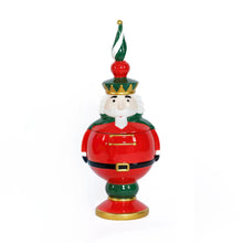 Load image into Gallery viewer, Hand-painted ceramic Nutcracker cookie jar in red, green, and gold with a black belt detail, white beard, and a tall red, green, and white finial, displayed against a white background.  