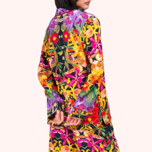 Load image into Gallery viewer, Botanical Kaleidoscope Pyjamas, back view of model wearing the long-sleeve viscose top and matching trousers in a vibrant multicolored floral rainforest pattern with black background, against a white background.
