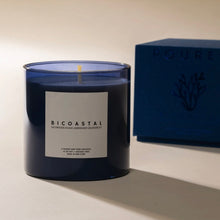 Load image into Gallery viewer, Poured NY Bicoastal candle in blue glass vessel, displayed on a white surface with coordinating blue packaging box in the background. 