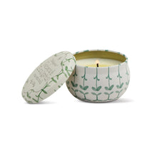 Load image into Gallery viewer, Round mini soy candle tin featuring green botanical design with matching lid, shown burning on a white background.