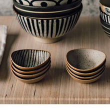 Load image into Gallery viewer, Unite Element Dipping dishes set, stoneware dishes with reactive glaze and black stripe on cream speckled interiors, beige textured exteriors, and tan rims, stacked on a wooden surface with coordinating bowls in the background.