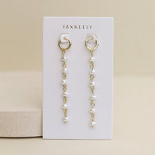 Load image into Gallery viewer, 18K gold-plated drop pearl earrings with six freshwater pearls suspended from a chain on a white JAXKELLY display card.