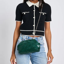 Load image into Gallery viewer, Model wearing a woven forest-green vegan-leather crossbody bag with a silver chain strap, styled with a black short-sleeve top with white accents and light-wash jeans against a white background. 