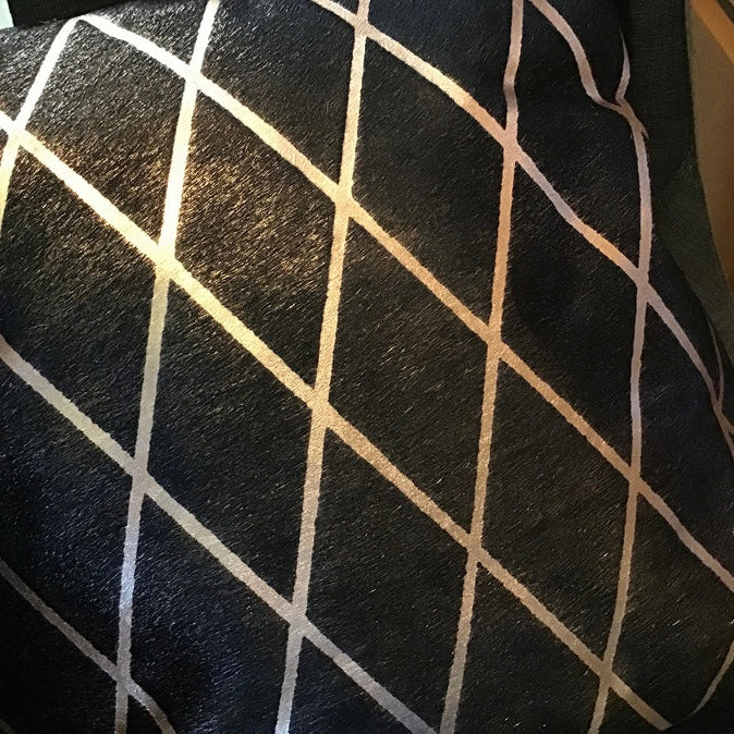Close-up of black hide pillow  with a white geometric pattern.