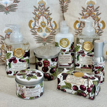 Load image into Gallery viewer, Michel Design Works Dark Cherry bath and body collection with foaming hand soaps, lotion, bar soap, candles, and room spray featuring cherry fruit and botanical label design displayed in front of a patterned pillow backdrop.  
