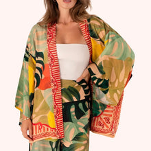 Load image into Gallery viewer, Exotic Leaves Kimono Jacket, lightweight open-front kimono with tropical leaf print in dark green, teal, beige, yellow, and coral with red patterned trim, shown on model against white background.  