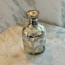 Load image into Gallery viewer, Silver Mercury Glass Etched Bud Vase, silver mercury glass etched bud vase with a rounded body and subtle flared neck, displayed on a light stone surface against a gray marble background. 