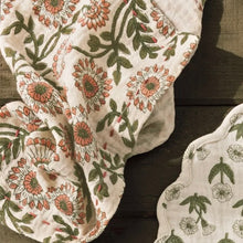 Load image into Gallery viewer, Thicket Double Weave Napkin, cotton napkin with floral pattern in peach and olive on a cream background with Kanthan-style stitching, shown on wood surface next to coordinating fabric.