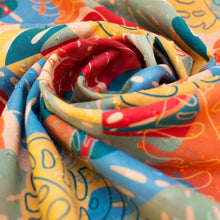 Load image into Gallery viewer, Exotic Leaves Infinity scarf, close-up of loosely gathered cotton fabric with multicolor abstract exotic leaf pattern in coral, red, light blue, green, and mustard tones. 