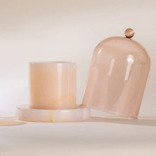 Load image into Gallery viewer, Poured NY pink onyx candle with translucent finish, matching lid, glass cloche and base, displayed on a white surface. 