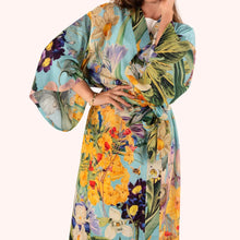 Load image into Gallery viewer, Spring Flora Kimono Gown worn by model, lightweight fabric with large floral pattern in yellow, green, and purple tones on a turquoise-blue background, tie belt, wide sleeves, against a white background.  