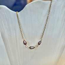 Load image into Gallery viewer, Lavender Freshwater Pearl Necklace, close-up view of a delicate 14k gold-filled chain with three oval freshwater pearls in lavender and silvery tones, showing their irregular surfaces and wire-wrapped connecting loops against a white ridged display.
