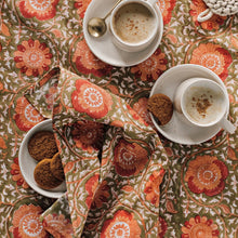 Load image into Gallery viewer, Zinnia Block Print Napkins, cotton napkins with hand block-printed floral pattern in coral and peach on an olive background, displayed with white coffee cups and saucers, and cookies on a matching surface. 
