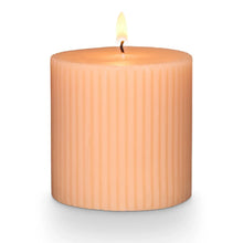 Load image into Gallery viewer, Paloma Petal Pillar Candle, lit peach ribbed pillar candle with single wick against white background. 