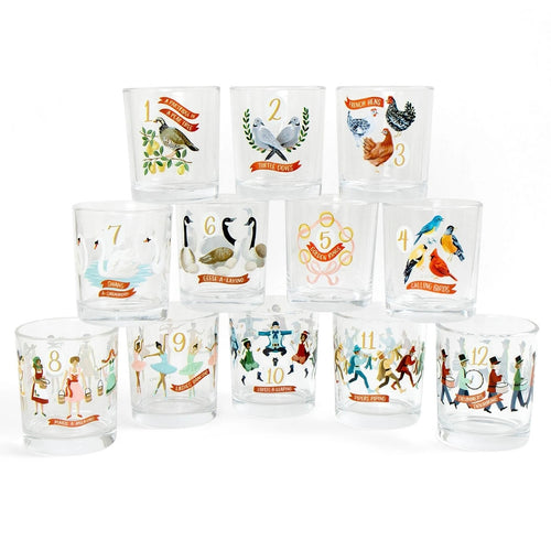 Set of twelve clear juice glasses, each hand painted with colorful illustrations and gold numbers for the twelve days of Christmas, arranged in three staggered rows against a white background. 