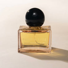 Load image into Gallery viewer, Poured NY Flesh &amp; Fuzz parfum in clear glass bottle with amber liquid and round black cap, displayed on a white surface. 