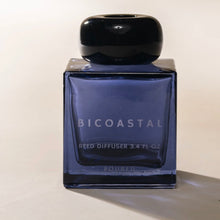 Load image into Gallery viewer, Poured NY Bicoastal reed diffuser in blue glass bottle with round black cap, displayed on a white surface. 