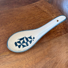Load image into Gallery viewer, White stoneware Geo Soup spoon with blue rim and tessellated triangular interior design, displayed on a wooden surface. 