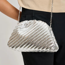 Load image into Gallery viewer, Silver woven vegan-leather half-moon crossbody bag with a silver chain strap worn over the shoulder against a neutral background. 