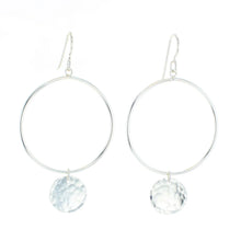 Load image into Gallery viewer, Pair of sterling silver hoop earrings featuring a hand-hammered round disc charm on each, displayed against a white background.