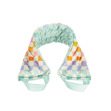 Load image into Gallery viewer, Weighted neck wrap in a rainbow-checkered pattern featuring blue, lavender, orange, pink, and white squares with light blue straps, displayed on a black and gray background. 