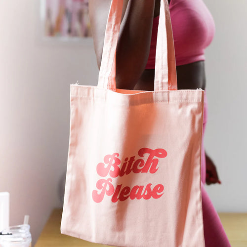 Person holding a light pink canvas bag with 