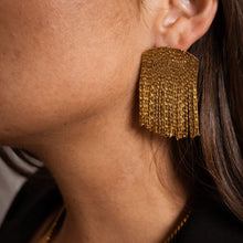 Load image into Gallery viewer, Close-up of a model wearing a gold-plated brass earring featuring wide cascading snake-chain fringe panels. 