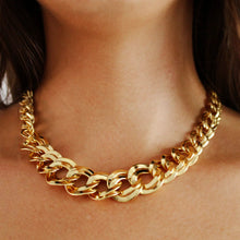 Load image into Gallery viewer, Model wearing the bold double-link Empress Necklace in gold-plated brass, showcasing its fluid, polished links resting at the collarbone.
