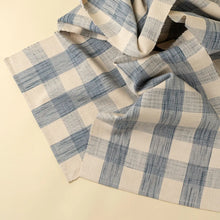 Load image into Gallery viewer, Blue-and-cream gingham table runner loosely draped and folded on a cream background.