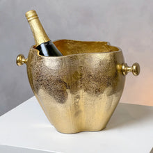 Load image into Gallery viewer, Sculpted wine cooler with a textured gold-finish and rounded side handles, holding a bottle of champagne and displayed on a white surface against a gray background. 