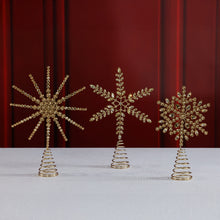 Load image into Gallery viewer, Three gold jeweled tree toppers in starburst and snowflake designs, each on a coiled spring base, displayed on a white surface in front of a red backdrop.