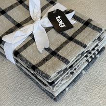 Load image into Gallery viewer, Canyon woven dishtowel set in cotton with black and ivory check pattern, folded and tied with white fabric ribbon and branded tag, shown on neutral textured surface. 